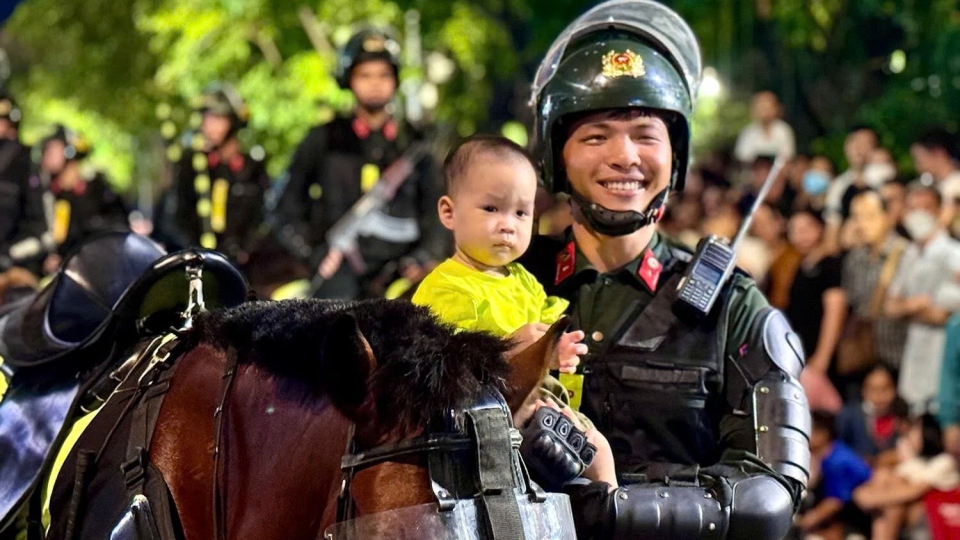 Crowds watch cavalry mobile police corps march along HCM City street