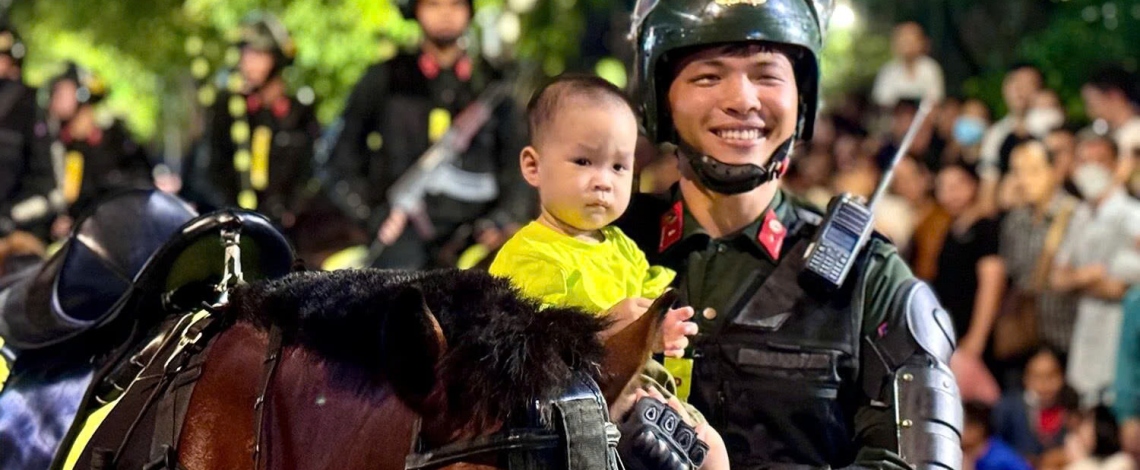 Crowds watch cavalry mobile police corps march along HCM City street